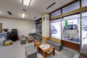 A lobby with a sofa, coffee table, and a large window with a view of parked cars.