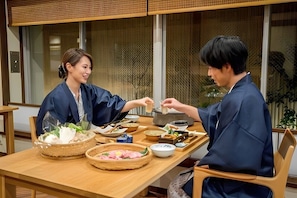 A traditional Japanese meal setting with a wooden table, various dishes, and a window with a view. - Ryokufuso (Kyoto)