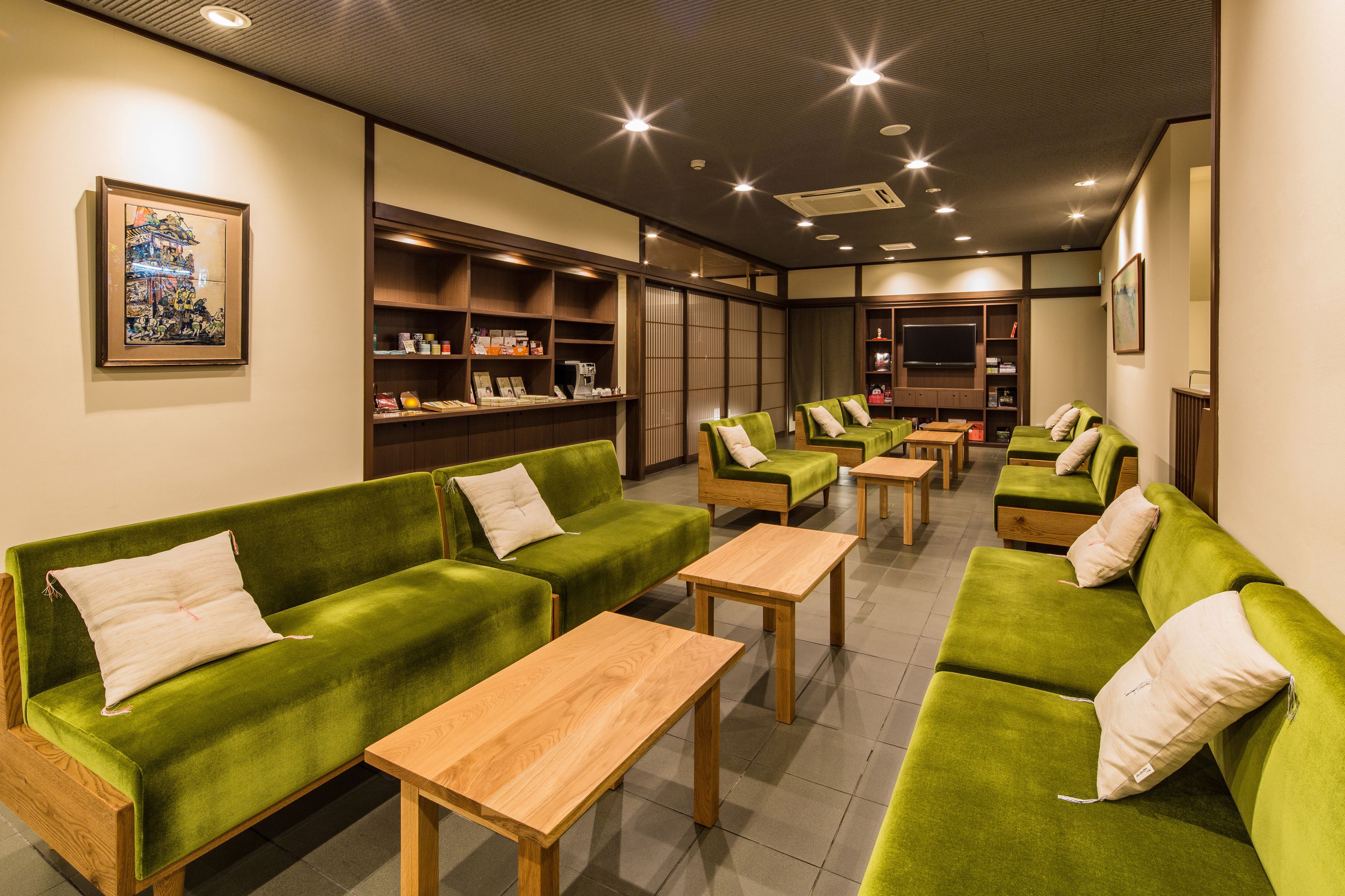 A hotel lobby with green sofas, wooden tables, and shelves with amenities.