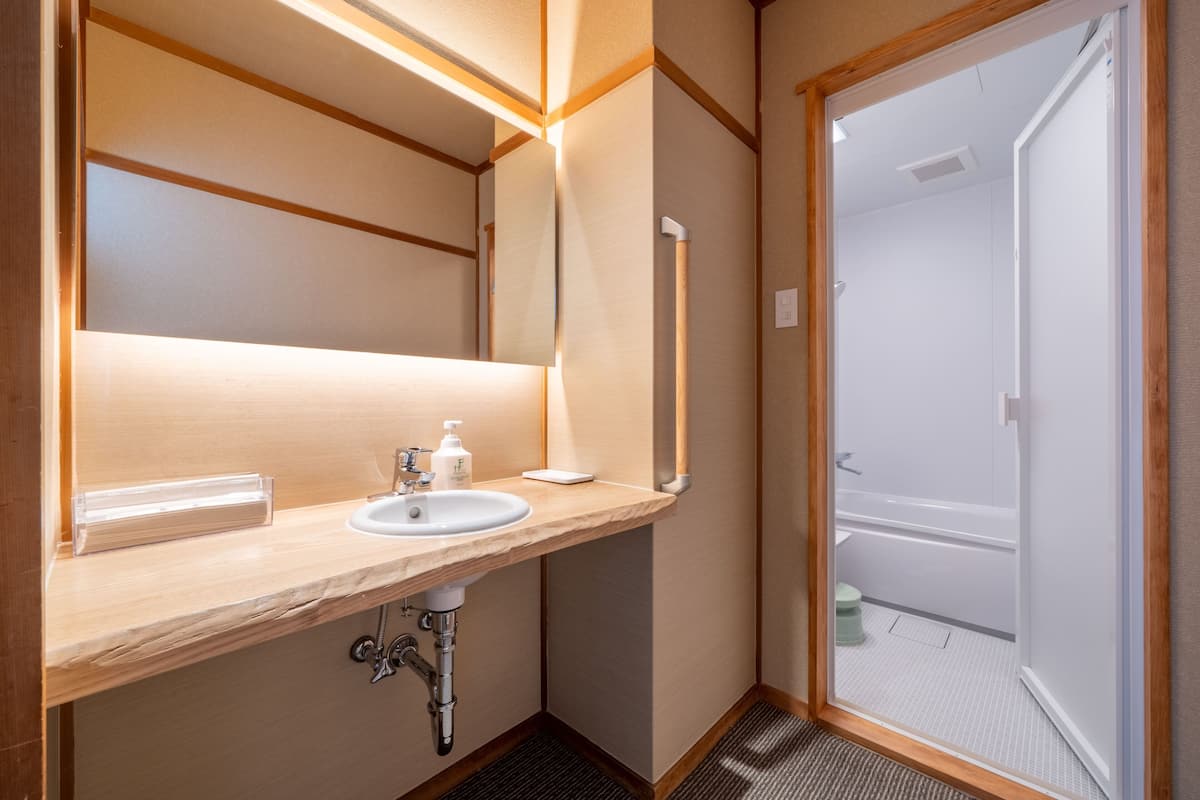 A bathroom with a wooden vanity, a sink, a mirror, and a shower area.