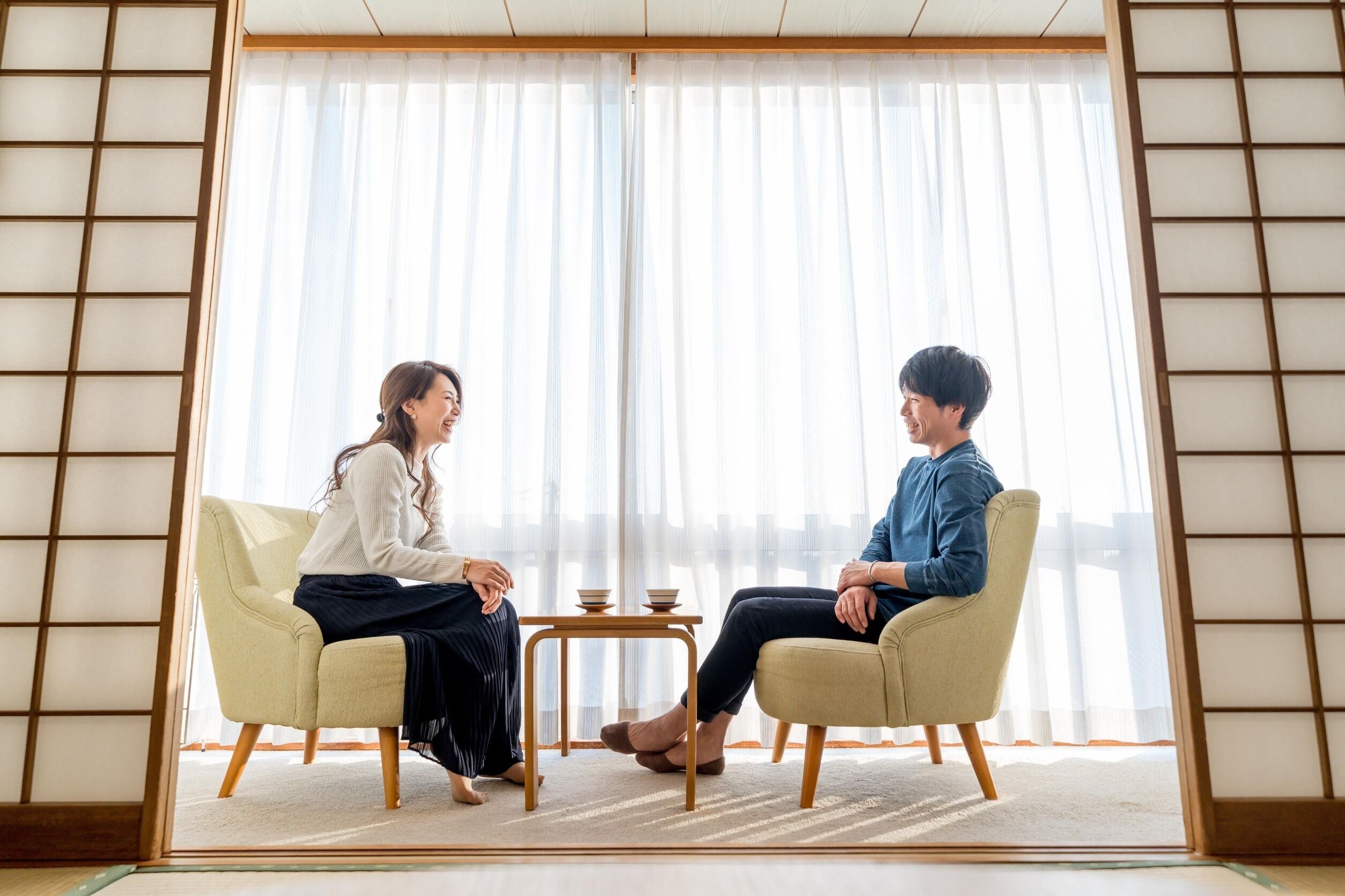 A room with tatami mat flooring, a low table with two bowls, and a traditional sliding door.