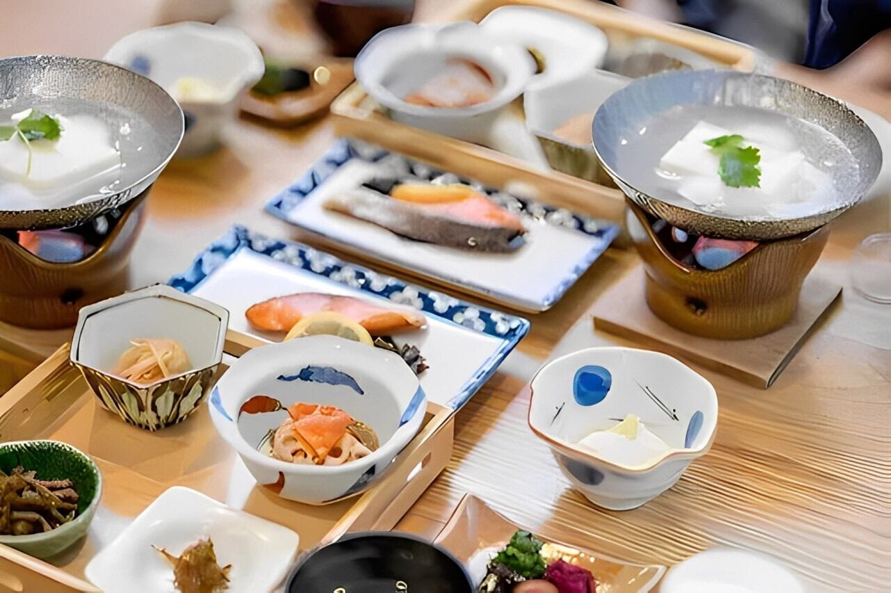 Une variété de plats japonais présentés sur un plateau en bois, notamment des sushis, des sashimis et d’autres spécialités à base de fruits de mer.