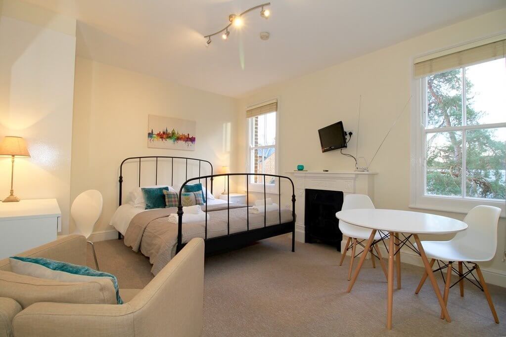 A bedroom with a bed, bedside table, chair, and a small dining table with chairs.