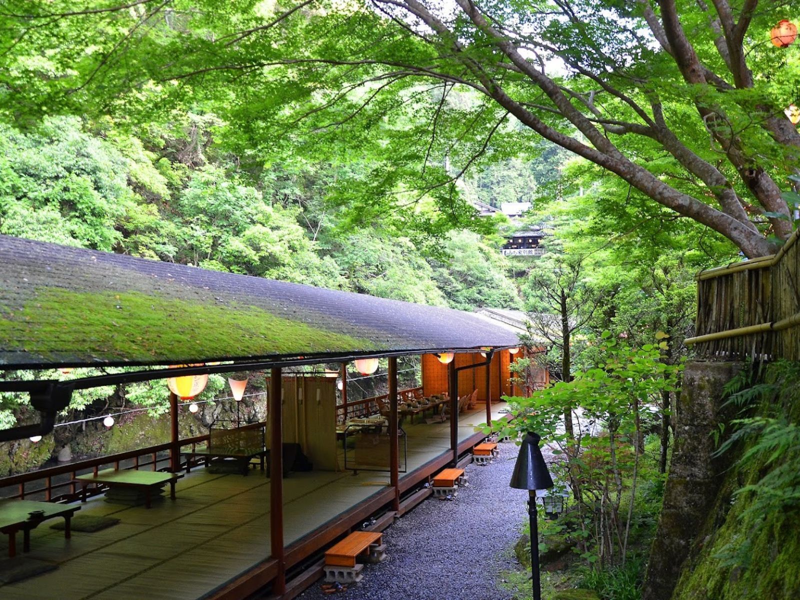 Una casa de té japonesa tradicional con suelo de esteras de tatami, bancos de madera y un área de estar cubierta al aire libre.