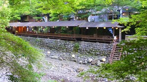 A traditional Japanese ryokan with a stone wall and wooden walkway.