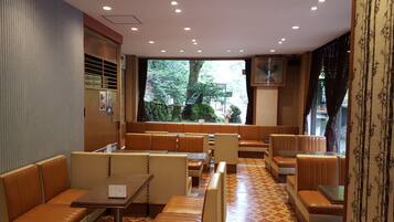 Un restaurante con cabinas y mesas, un suelo estampado y vistas a árboles desde el exterior.