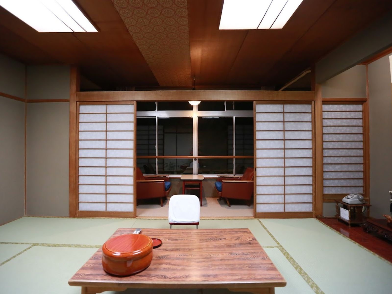 Une pièce avec un sol recouvert de tatamis, une table basse en tatami, une table traditionnelle japonaise et une porte coulissante en papier de riz (shoji).