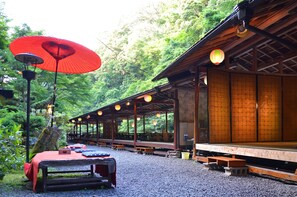 A traditional Japanese inn with tatami mat rooms, wooden beams, and a covered outdoor seating area.
