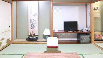 A traditional Japanese room with tatami flooring, a low table, a television, and a small cabinet.