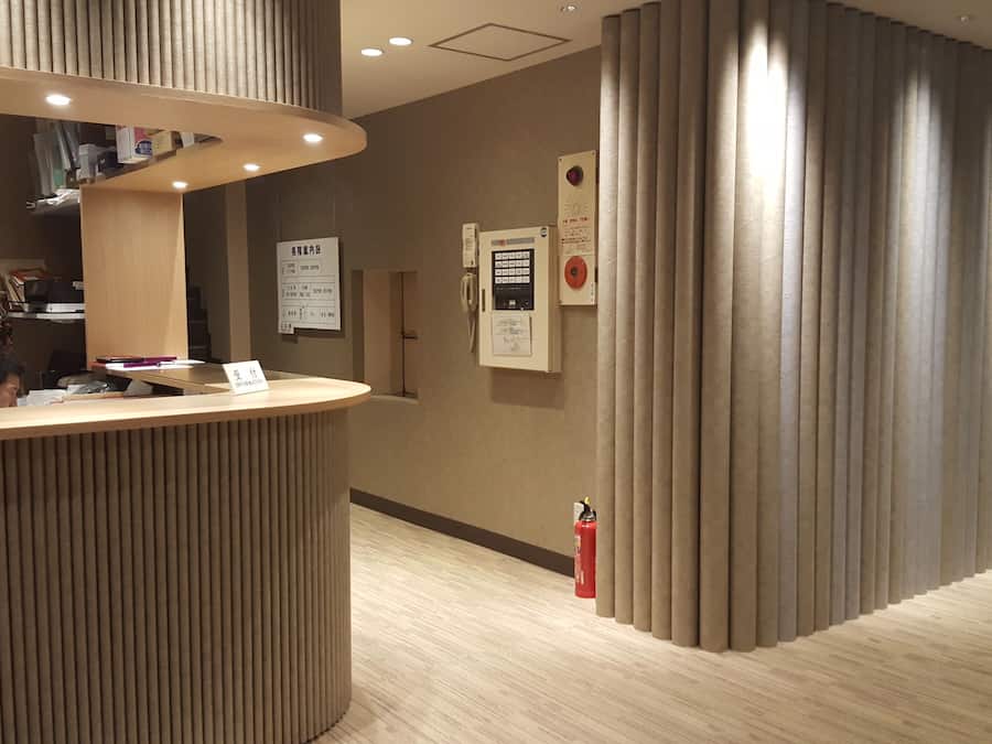 Un espace d’accueil avec un comptoir de réception en bois, un extincteur et des panneaux d’information sur le mur.