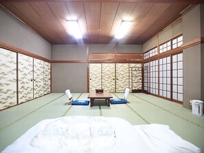 Una habitación japonesa tradicional con suelo de tatami, una mesa baja y puertas correderas.