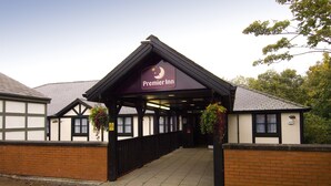 A hotel entrance with a sign reading 'Premier Inn,' a covered walkway, and a brick wall. - Premier Inn Manchester - Swinton (Manchester)