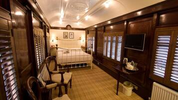 A bedroom with a large bed, wooden wardrobe, a television, and a radiator.