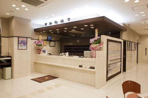 A reception desk with a digital screen, a clock, and a bulletin board.