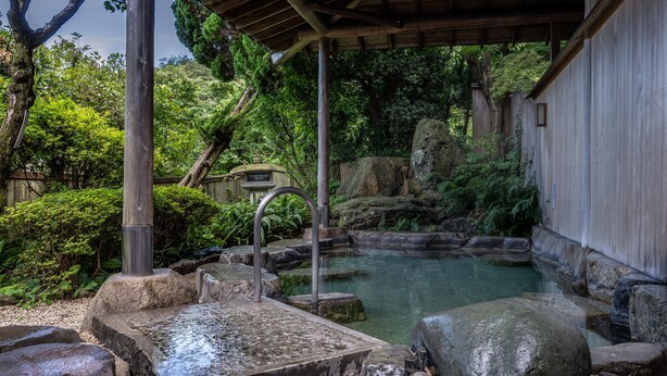 A traditional Japanese garden with a stone bath, wooden structures, and lush greenery. - Senpokaku (Toba)