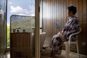 A person sitting on a white chair in a wooden room with a toilet and a sink. - Senpokaku (Toba)
