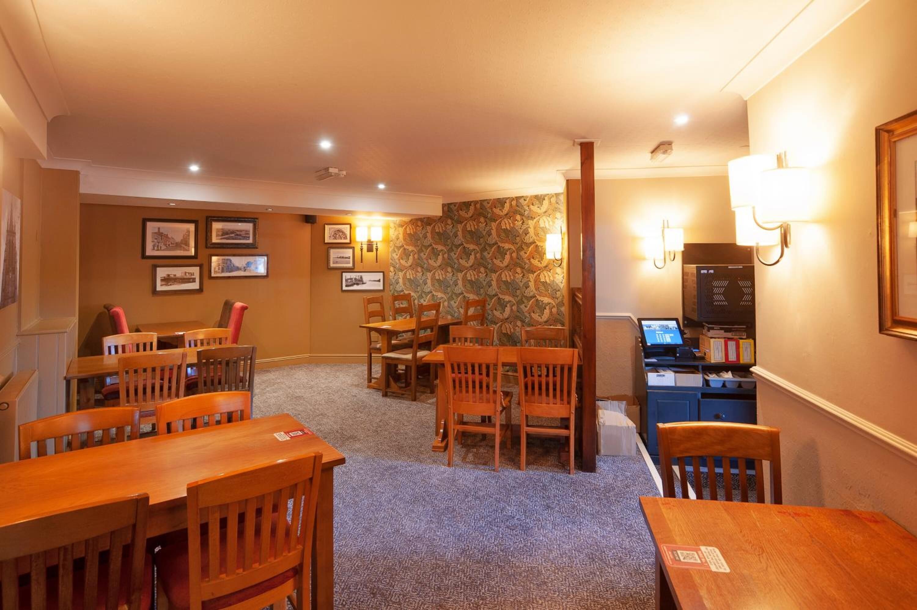 A hotel room with a dining area, a desk with a computer, and a carpeted floor.