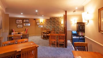 A hotel room with a dining area, a desk with a computer, and a carpeted floor.