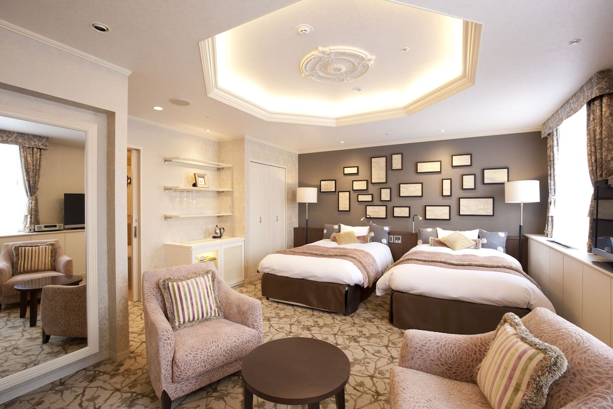 Habitación de hotel con dos camas, un sofá, una mesita y un espejo.