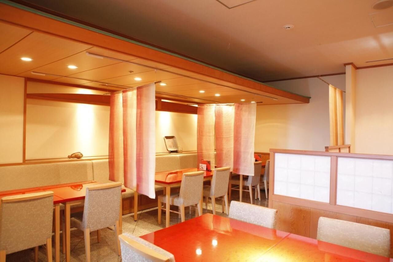 A hotel room with a wooden ceiling, a red table, and several chairs.