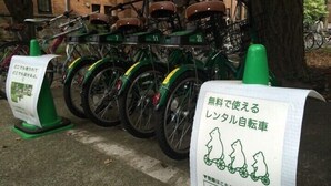 En række grønne cykler med numrene 7, 11 og 20, og et skilt med japansk tekst.