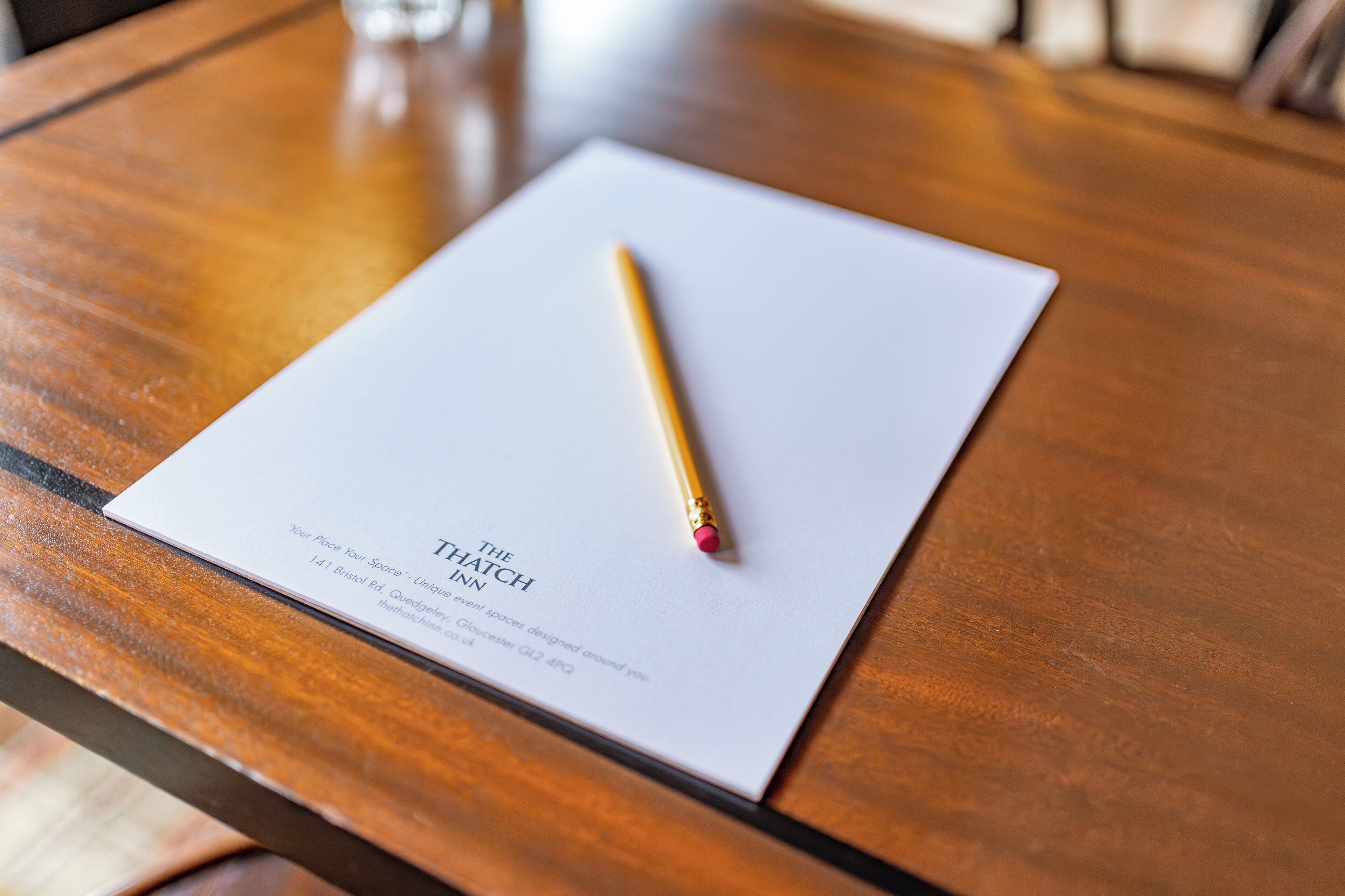 A white paper titled "The Flatch Inn" on a wooden table with a gold pen on it.