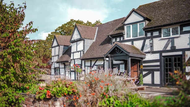 Un edificio de estilo Tudor tradicional con varios tejados a dos aguas y entramado de madera blanco y oscuro.