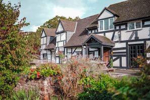 Un edificio de estilo Tudor tradicional con varios tejados a dos aguas y entramado de madera blanco y oscuro.