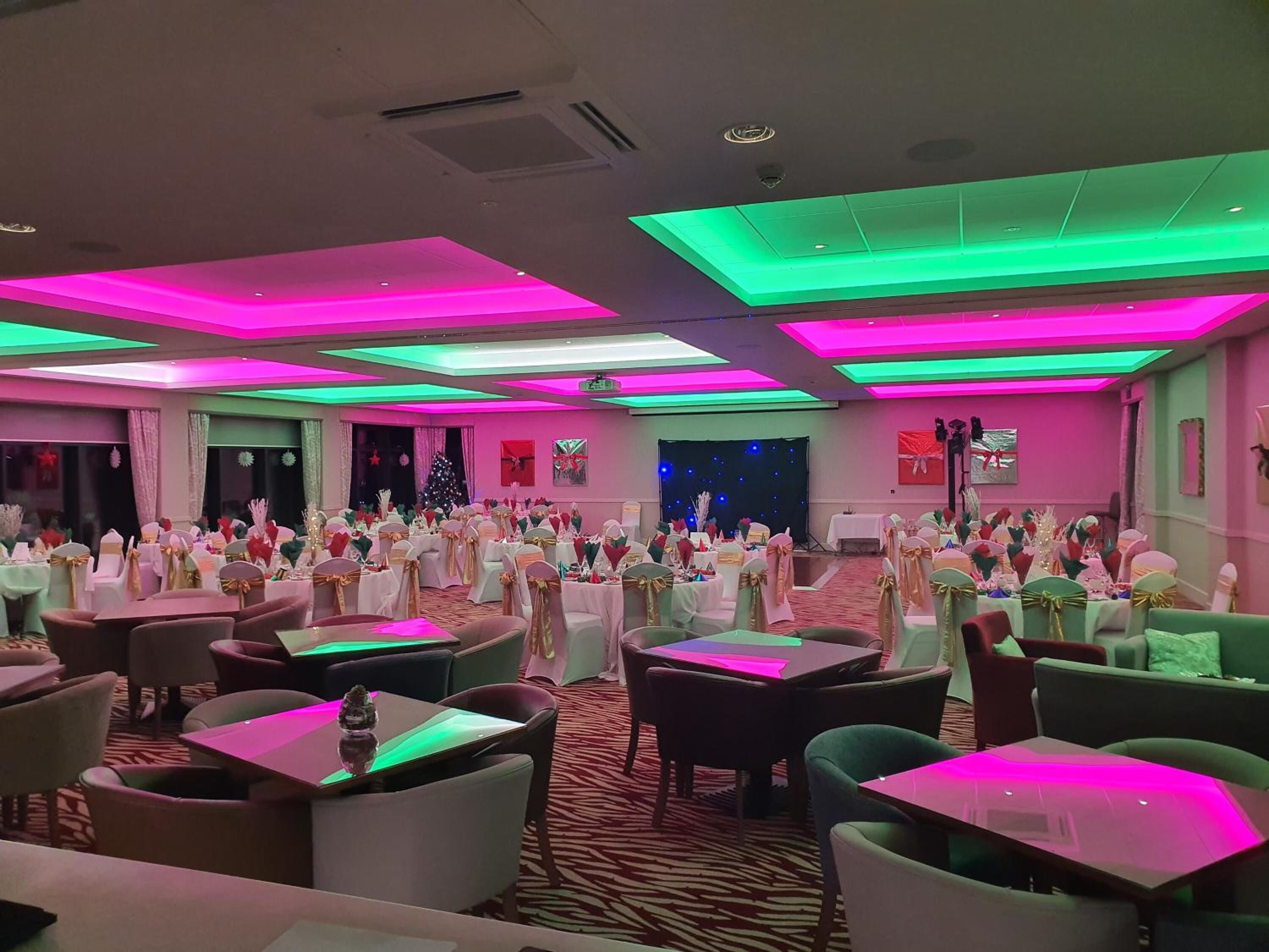 Un salón de banquetes con mesas dispuestas para un evento formal, con alfombra de estampado de cebra y luces en el techo.