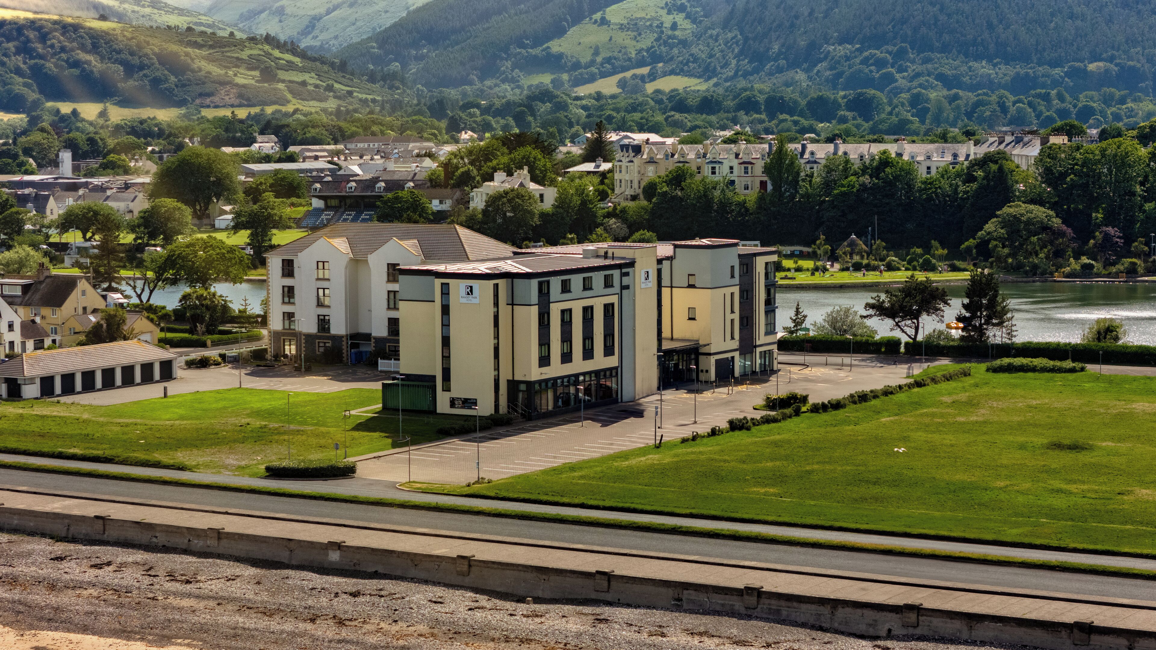 Un hotel con diseño arquitectónico moderno, situado cerca de agua y con vistas panorámicas de colinas al fondo.