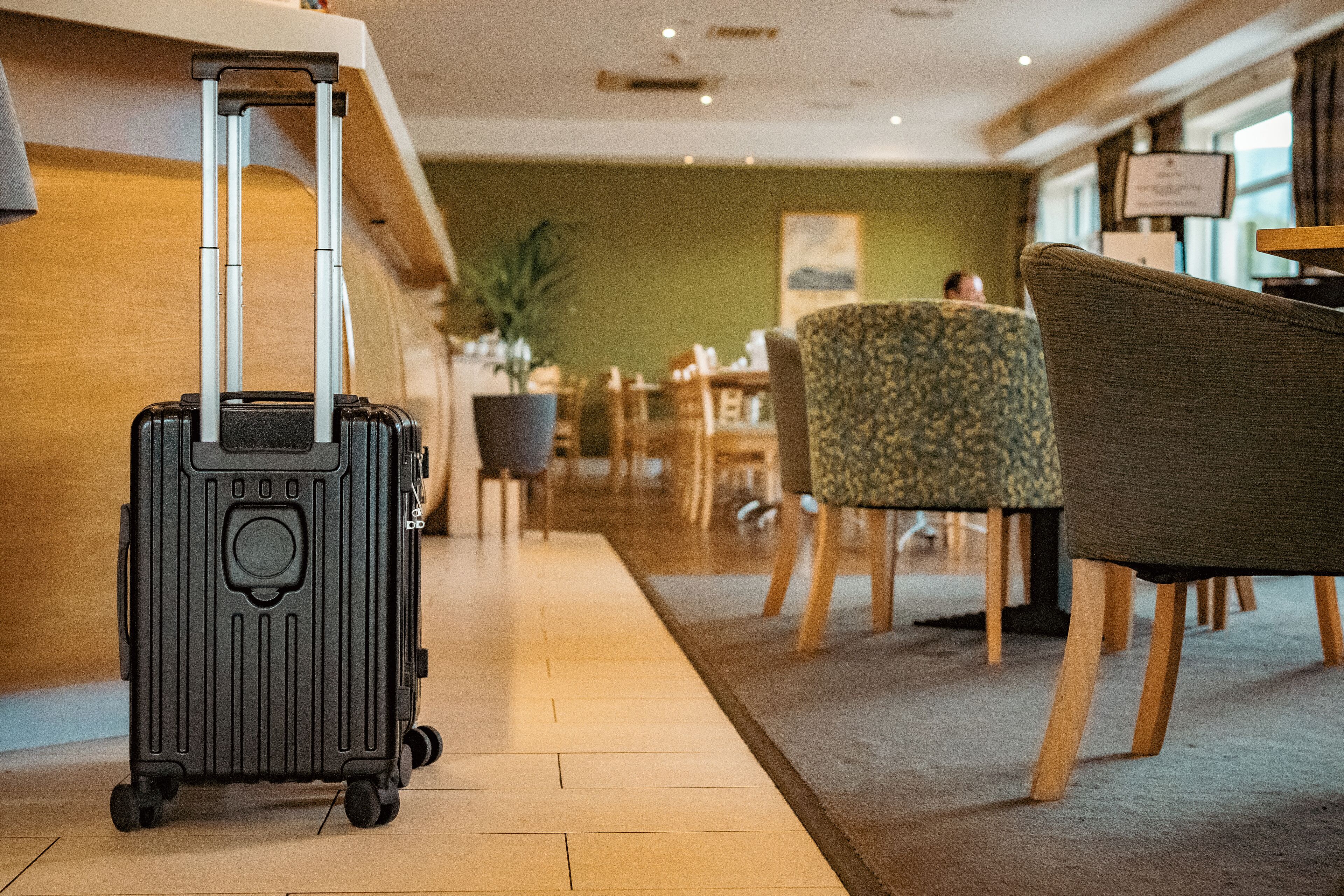 Un hall d’hôtel comprenant un comptoir d’accueil, un espace salon et une valise.