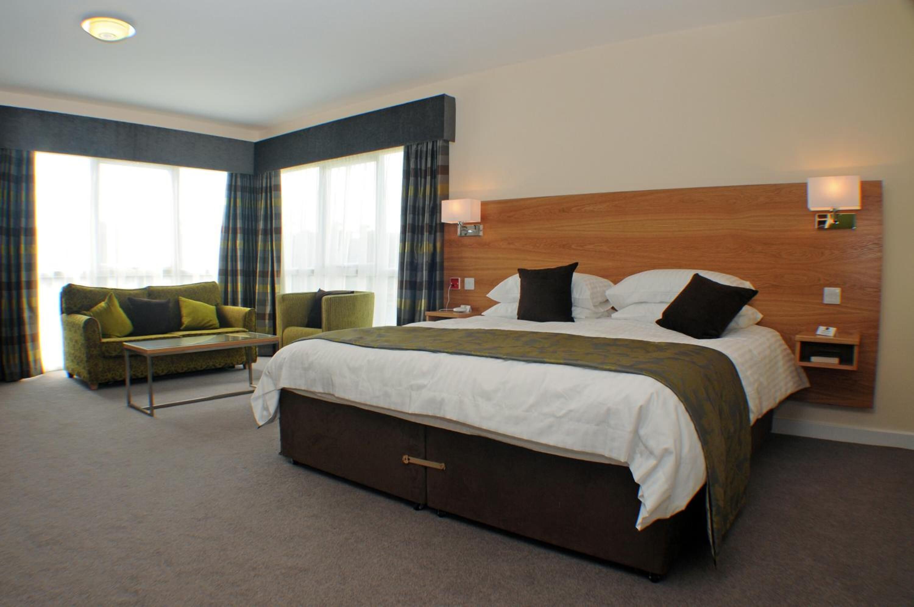 Een hotelkamer met een groot bed, een bank en een raam met gordijnen.