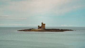 Un faro en una pequeña isla con aguas tranquilas y cielo despejado.