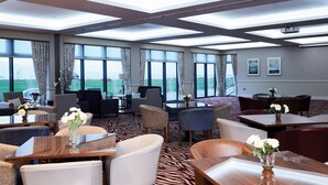 A hotel lobby with multiple seating areas, large windows, and a view of the outside.