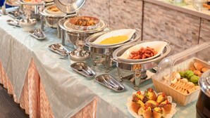 A buffet with various food items in metal containers, a wicker basket with bread, and a tiled wall in the background. - Hotel Sun Valley Annex (Beppu)