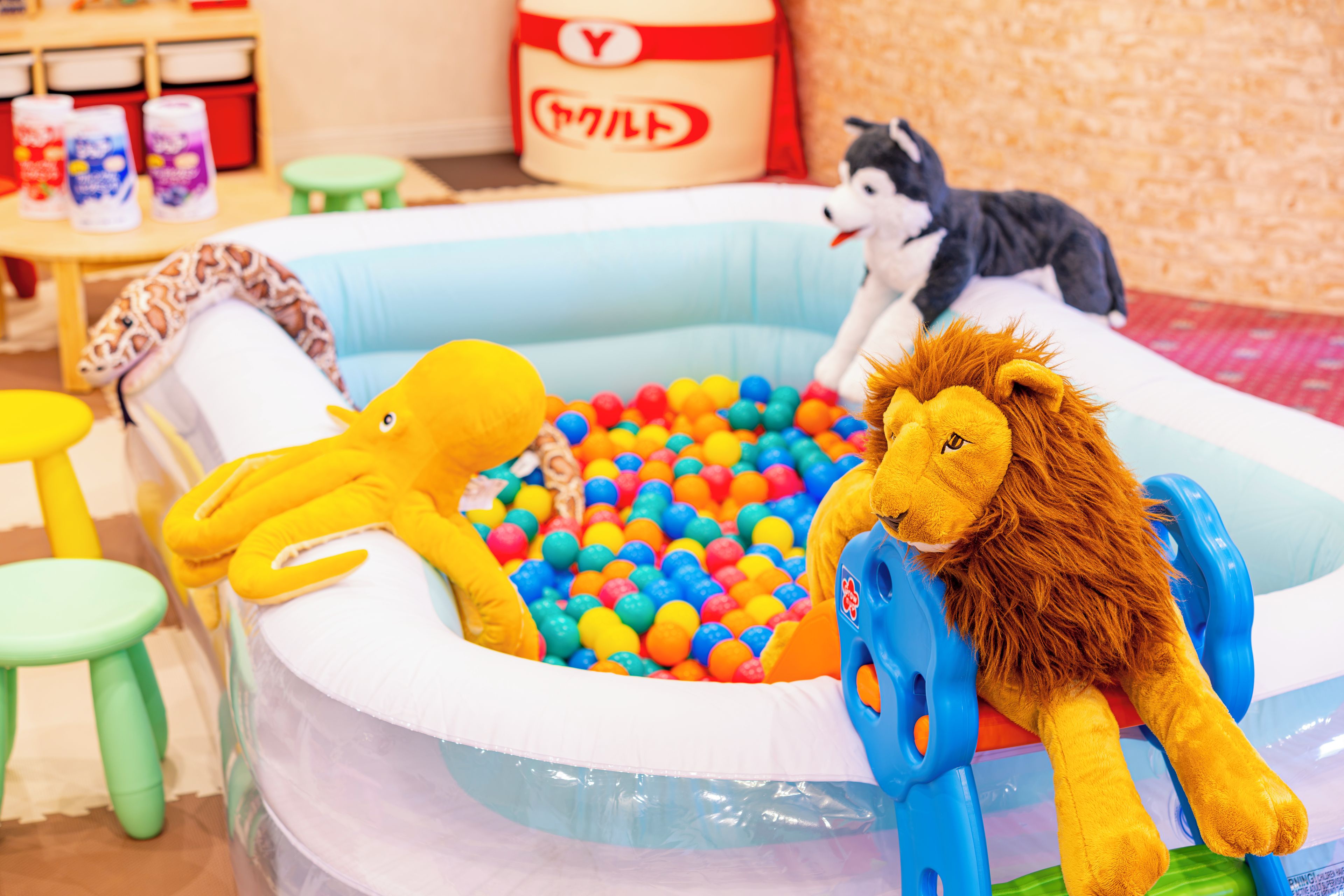 Una piscina inflable para niños llena de bolas de plástico de colores, rodeada de peluches.