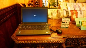 A laptop on a wooden table with a mouse and a mouse pad, surrounded by various packaged goods.
