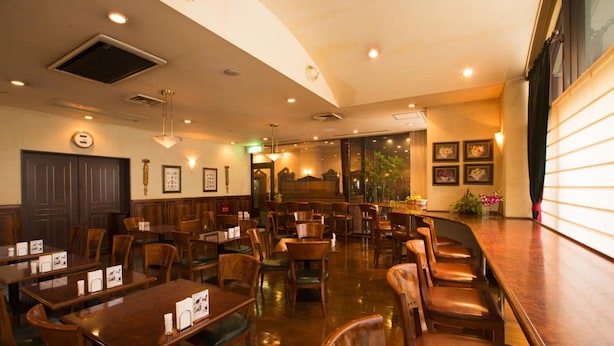 A restaurant with wooden tables and chairs, a bar area, and framed pictures on the walls.