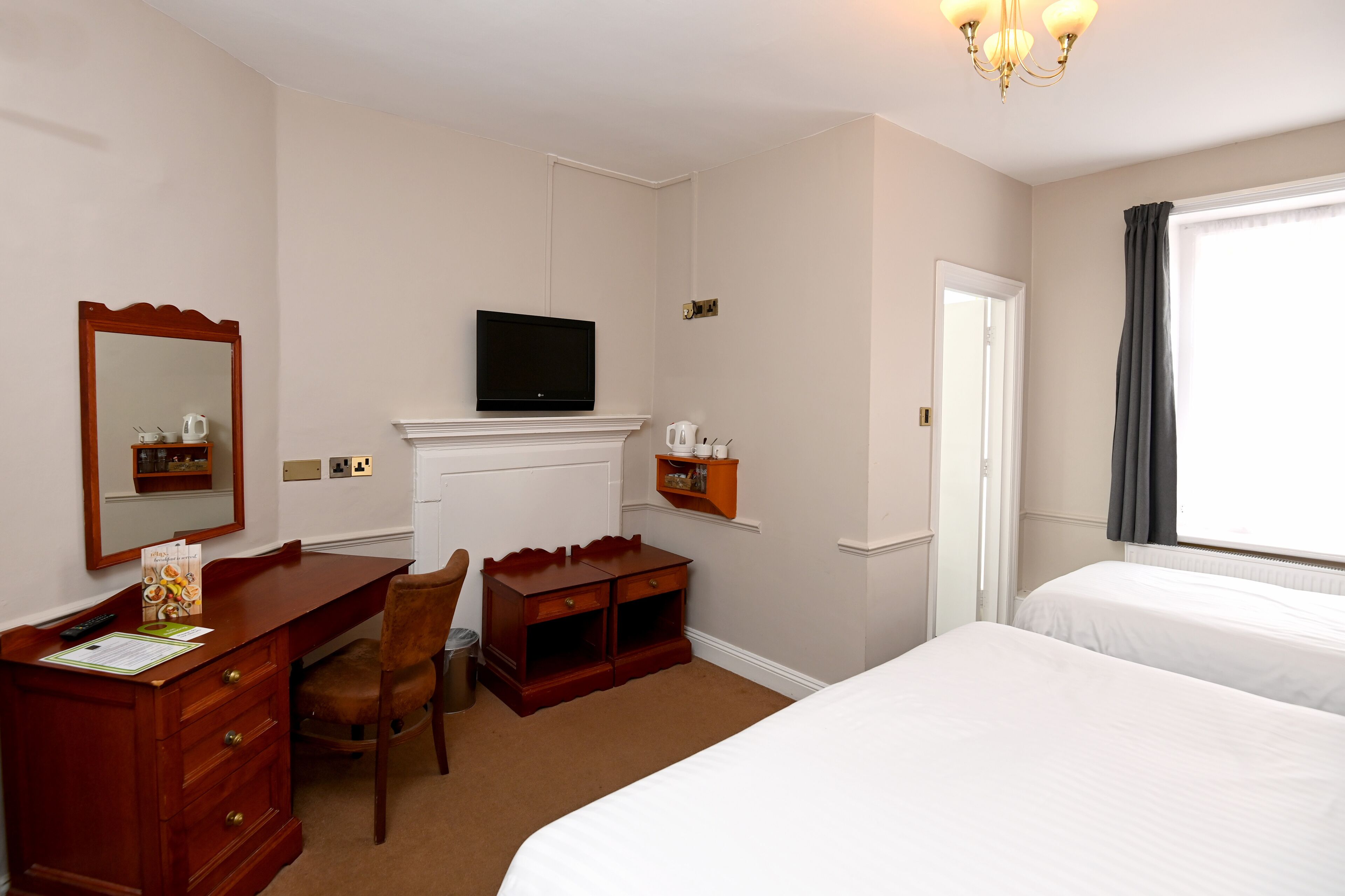 Une chambre d’hôtel équipée d’un lit, d’un bureau, d’une chaise, d’une télévision et d’une petite armoire.