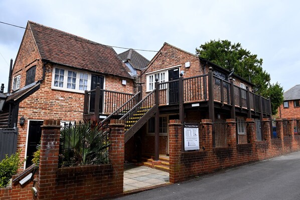 A brick building with a staircase leading to a balcony. - Original White Hart, Ringwood by Marston's Inns (Ringwood)