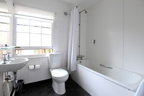 Enjoy a clean and functional bathroom with a standalone sink, toilet, and bathtub with showerhead.