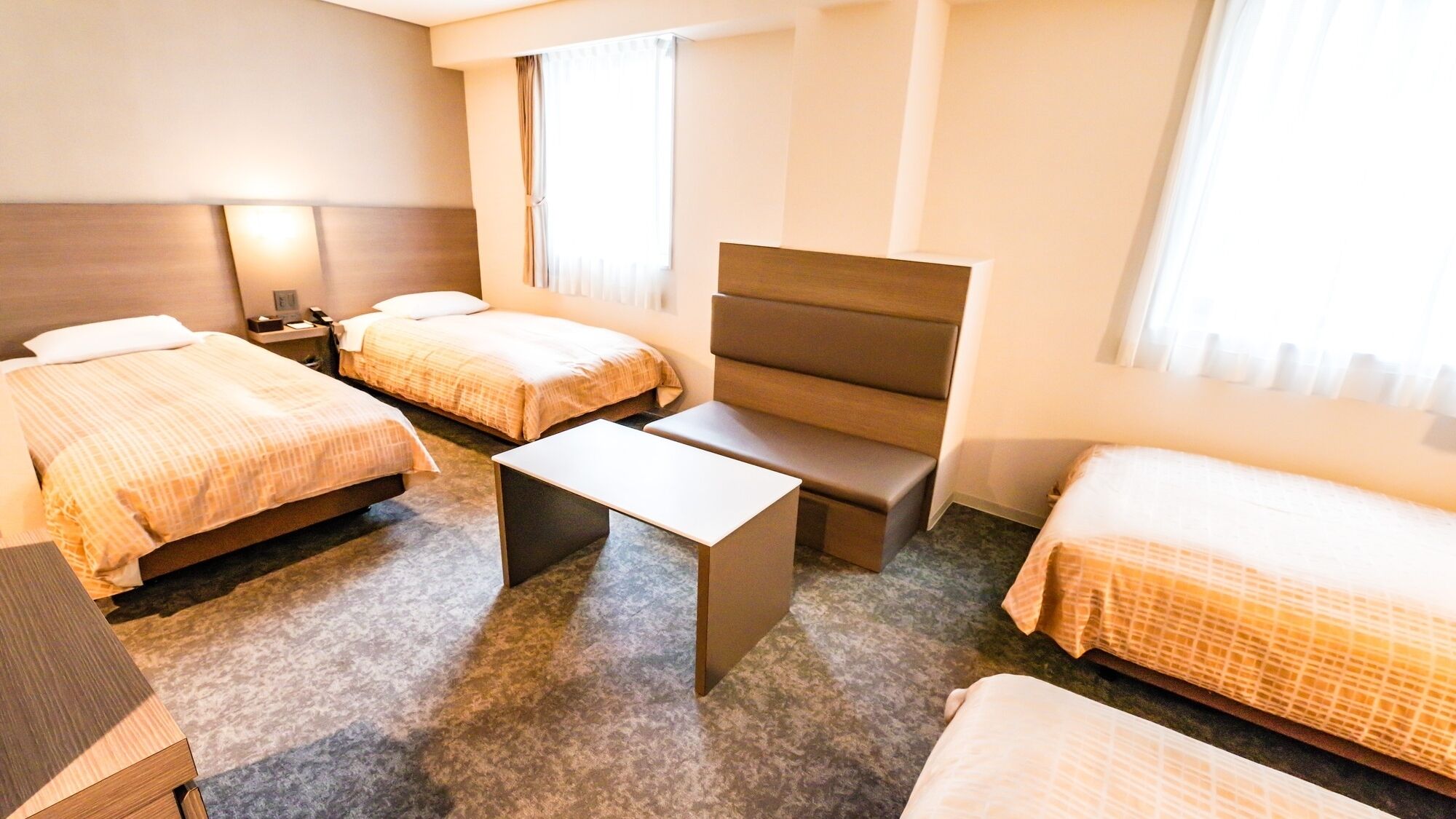 A hotel room with two beds, a sofa, a small table, and a nightstand.