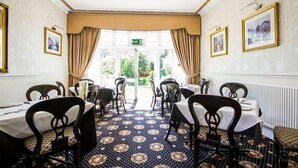 A dining area with tables and chairs, a patterned floor, and framed pictures on the walls. - Norman Hurst (Sale)