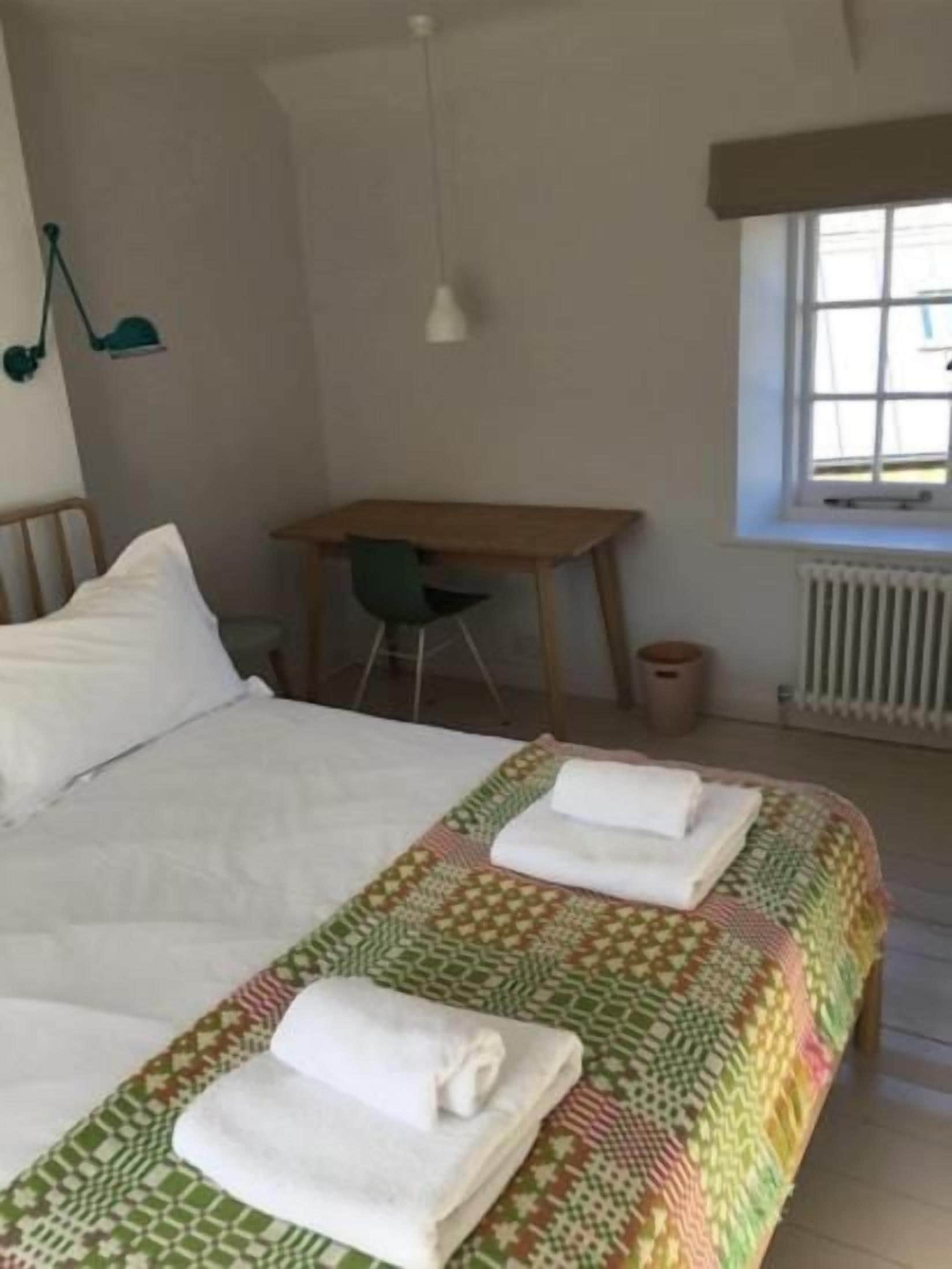 Una habitación de hotel con una cama grande, un escritorio y una silla.