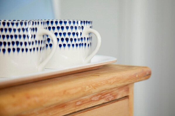 A white ceramic mug with a blue pattern and a handle, placed on a wooden surface.