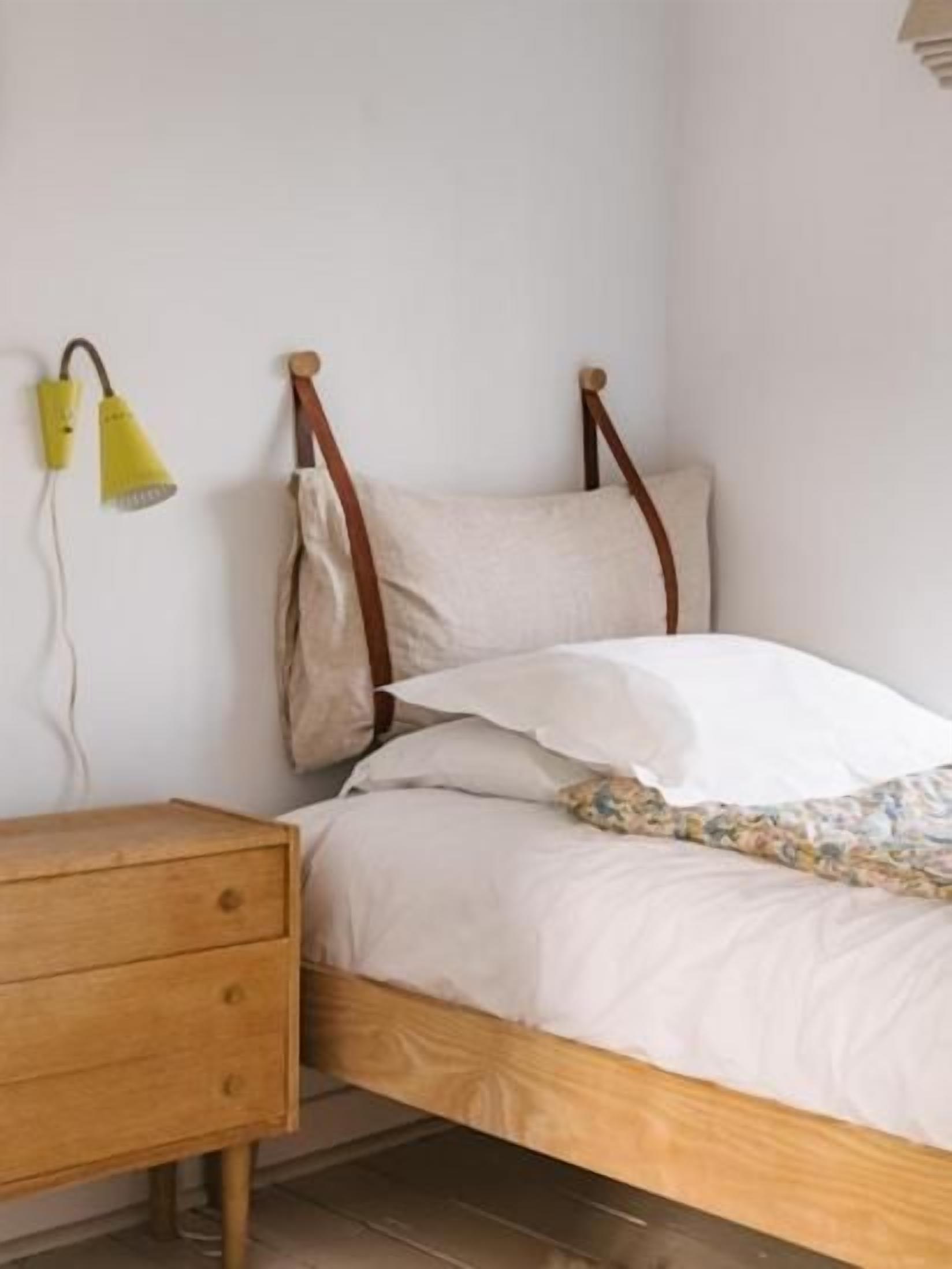 A single bed with a wooden frame, a bedside table, and a lamp.