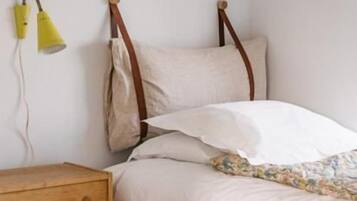 A single bed with a wooden frame, a bedside table, and a lamp.