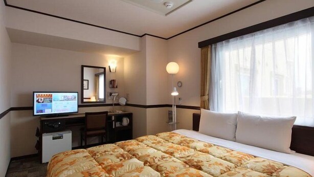 A hotel room with a large bed, a desk, a television, and a window with curtains. - Toyoko Inn Kagoshima Chuo-eki Nishi-guchi (KAGOSHIMA)