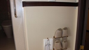 A bathroom with a towel rack holding a white towel and a pair of slippers. - Toyoko Inn Kagoshima Chuo-eki Nishi-guchi (KAGOSHIMA)