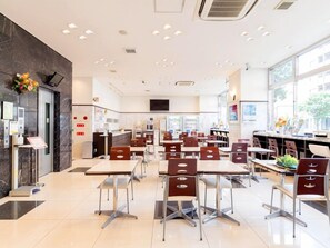 A spacious restaurant with multiple tables and chairs, a counter area, and large windows providing natural light. - Toyoko Inn Kagoshima Chuo-eki Nishi-guchi (KAGOSHIMA)